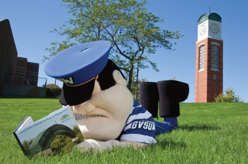Louie the Laker lying on the grass near a clock tower